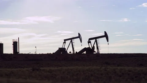 Driving by two active oil pumps in silhouette in Vernal Utah oilfield Video stock 202614275