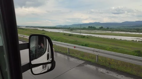 Driving van on wet highway with mountain view and river Stock Footage 346885244