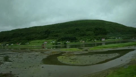 Driving view of low tide mudflats and red cabins along Norwegian fjord Stock Footage 341814604