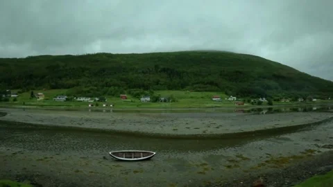 Driving view of low tide mudflats with wooden rowboat and red shed in Norway Stock-Footage 341814609