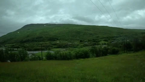 Driving view of lush green mountain valley and river in Northern Norway Vidéo 341814608