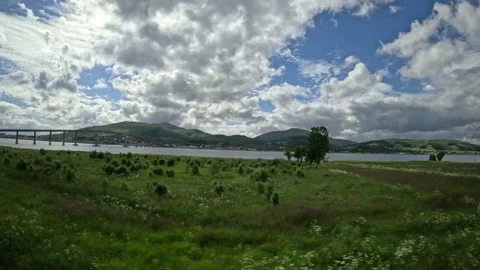 Driving view past green meadow towards coastal fjord and bridge in Norway Vidéo 343380245