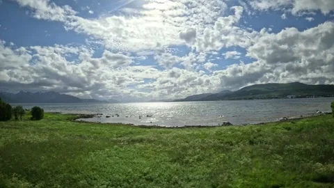 Driving view past traditional red cabins towards glittering fjord in Norway Vidéo 343380309