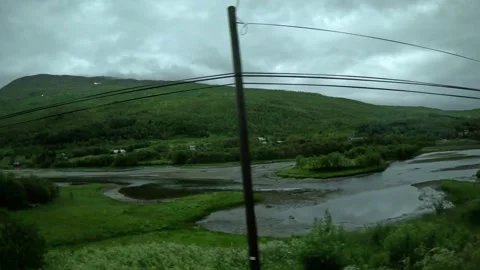 Driving view of river delta and red wooden cabins in green Norwegian valley Vidéo 341814605