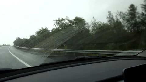 Driving on wet highway through rain with windshield wipers clearing water. Video stock 333829778