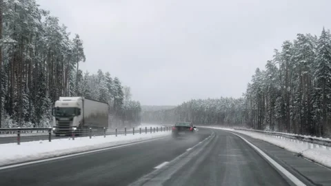 Driving on a wet winter highway through a snowy pine forest Stock Footage 323375615