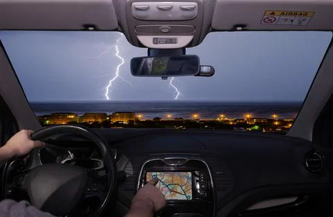 Driving while using navigation system towards lightning over the sea Stock Photos