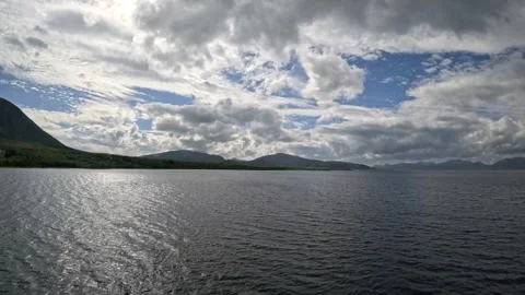 Driving wide view along ocean fjord and mountains under cloudy sky in Norway Stock-Footage 343380246
