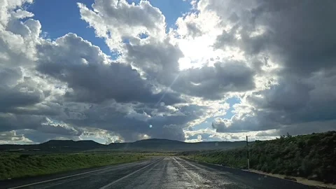 Driving on Winding Road with Sun Rays Breaking Through Storm Clouds 動画素材 335490013