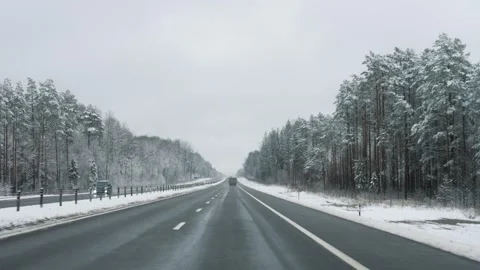Driving on winter highway through snowy forest landscape Video stock 323762079