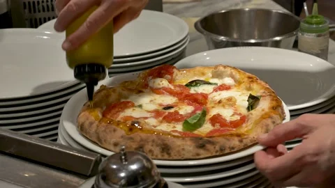 A drizzle of extra virgin olive oil over a freshly baked pizza margherita. Vídeo Stock 141804013