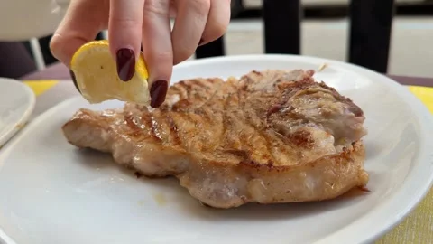 Drizzle lemon juice over the pork steak Stock Footage 323925273