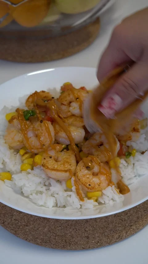 Drizzling Chipotle Sauce over Rice with Corn and Shrimp on White Plate Stock Footage 288919682