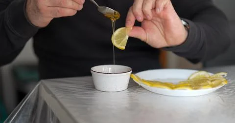 Drizzling golden elixir onto a lemon slice creating a sweet and sour symphony 库存照片