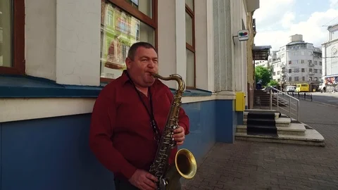 DROGOBYCH, UKRAINE - 3 MAY, 2019: Street musician in red shirt playing saxophone Video stock 108849564