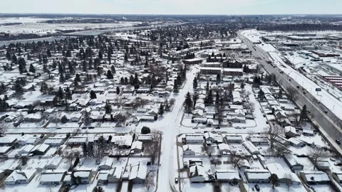 Dron shot captures a snowy residential area with a river Vídeos de archivo 334010789