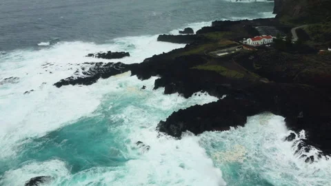 Drone 4K close to cliff on peninsula with crashing waves and isolated house Stock Footage 315265635