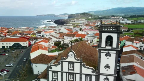 Drone 4K flying above town and church on cliff with sea and distant hills Stock Footage 315257501