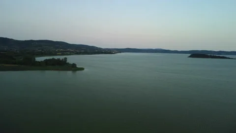 Drone 4K flying backward over green lakeshore and lake at sunset Stock Footage 315267883