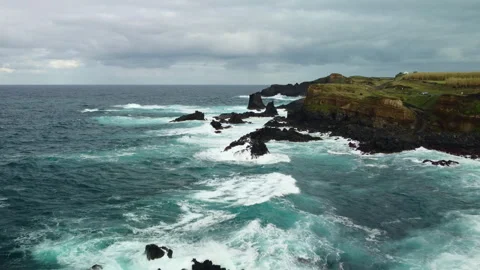 Drone 4K flying close to cliff with waves crashing on rocks and green top Stock Footage 315248722
