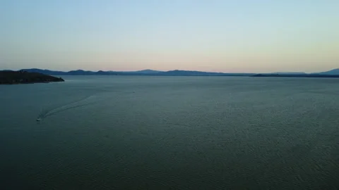 Drone 4K flying forward over lake with approaching boats and distant green shore Stock Footage 315271275