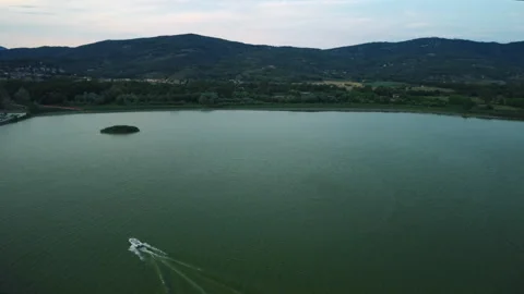 Drone 4K flying forward toward lakeshore harbor, town, and mountains at sunset Stock Footage 315270987