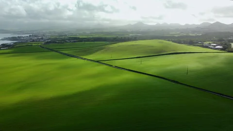 Drone 4K flying left-to-right over solitary road and vibrant green fields Stock Footage 315254496