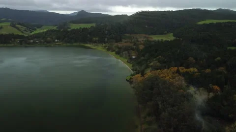 Drone 4K flying left to right over chapel, lake, and green forested hills Stock Footage 315259202