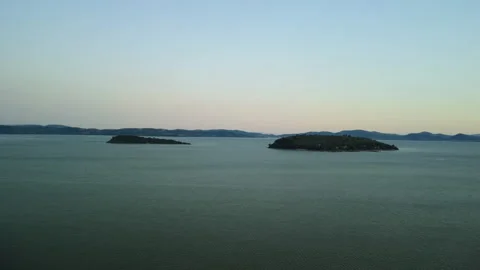 Drone 4K flying left-to-right over lake with green islands and lakeshore town Stock Footage 315269042