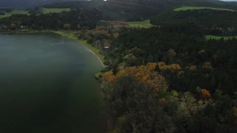 Drone 4K right-to-left over gothic chapel by lake with forested hills Stock Footage 315259389
