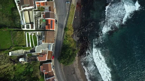 Drone 4K top-down over cliff, beach, road, and town with crashing waves Stock Footage 315255511