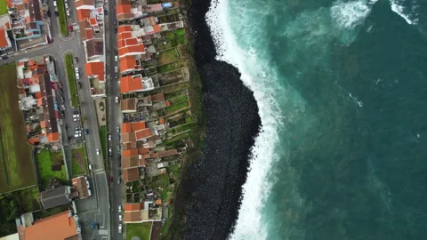 Drone 4K top-down over cliff, town, and rough sea waves Stock Footage 315256062