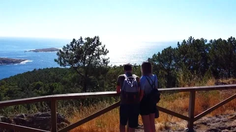 Drone advancing from behind a young couple to an amazing galician landscape w Stock Footage 136334655