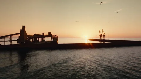 Drone aerial 4K pullback on industrial harbor pier with cargo cranes at sunset Stock Footage 333363970