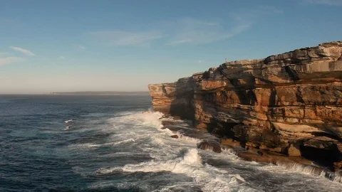 Drone aerial of breaking ocean waves along steep cliff in morning light Stock Footage 108731182