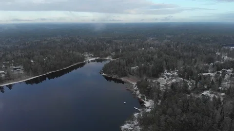 Drone aerial flying inside clouds over frozen shore, houses, trees and a lake Stock Footage 104504568