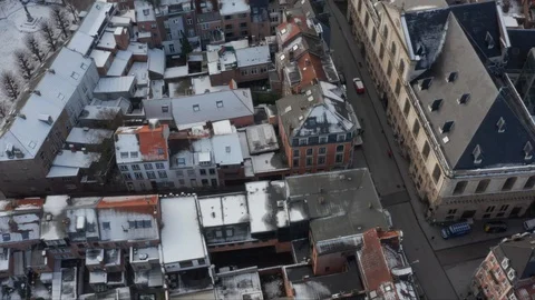 Drone Aerial flying over rooftops in city in the winter snow in Leuven Belgium 動画素材 123124500