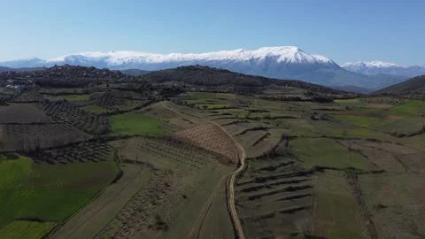 Drone Aerial Lush Green Fields and Snoly Mountain Stock Footage 244757873