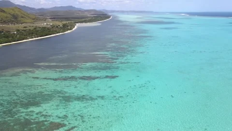 Drone aerial moving down and panning over a blue ocean and showing a Stock Footage 319059842