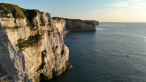 Drone aerial pan right over white chalk cliffs, golden hour, calm sea, Etretat Stock Footage 346477093
