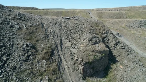 Drone aerial pull back to reveal cyclists pushing bikes up mountain trail Video stock 106072450
