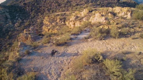 Drone aerial pullaway tracking motorcycle on desolate Arizona rocky landscape Stock Footage 78498571