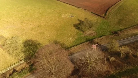 Drone Aerial of Red British tractor driving on UK roads through farming field Stock Footage 88282950