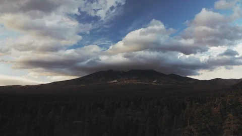 Drone aerial shot flying toward mountains with dramatic clouds over pine forest Stock Footage 127267953
