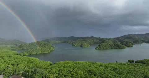 Drone aerial of storm clouds with rainbow above pacific island formation Stock Footage 332704692