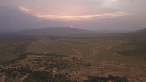 Drone aerial tilting down from a sunset to a Maasai Mara village in Serengeti Stock-Footage 249348649