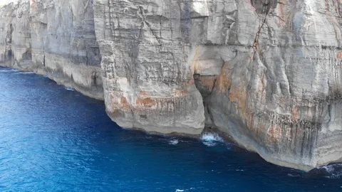 Drone aerial tracking shot of waves hitting rock cliffs revealing whole island Stock Footage 111267584