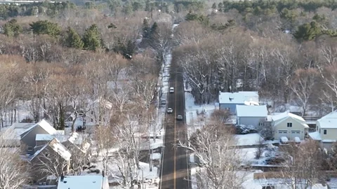 Drone Aerial Tracking Shot: White Vehicles Driving Through Snowy Suburban Street Stock Footage 296074985