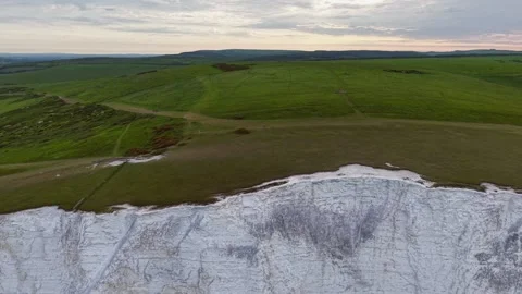 Drone aerial view of dramatic white cliff line merging with vast green fields Stock Footage 309764530