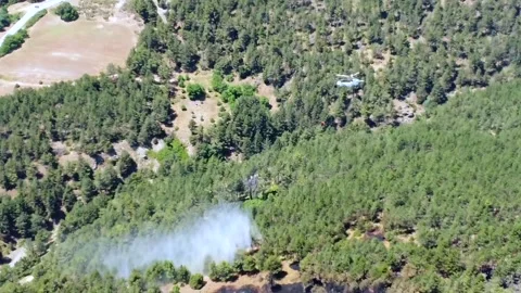 Drone aerial view of firefighting helicopter dropping water on forest fire in Stock Footage 345326370